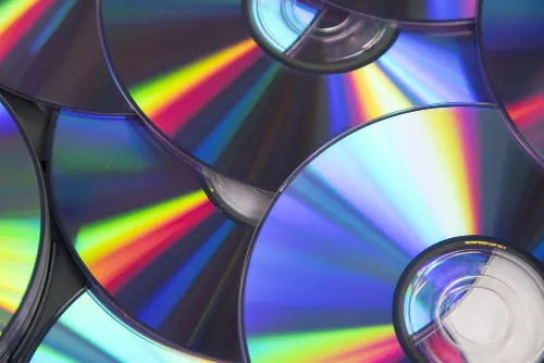 Discos de mídia física com reflexos coloridos.